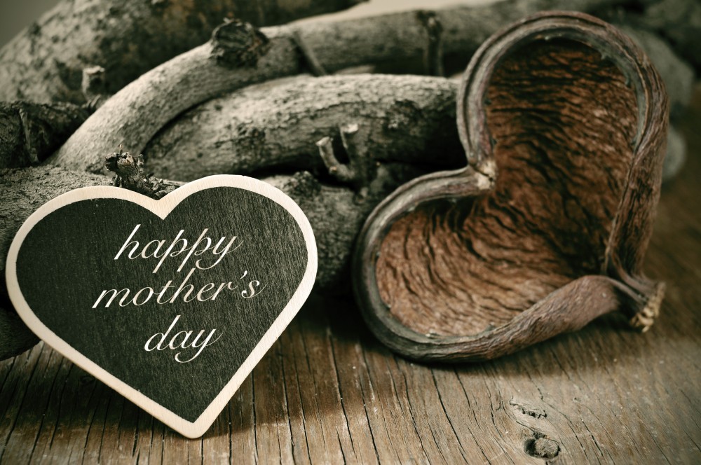 happy mothers day in a heart-shaped chalkboard on a rustic background